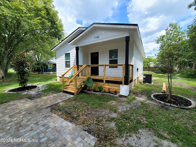 view of front of home with covered porch, central AC unit, and a front lawn