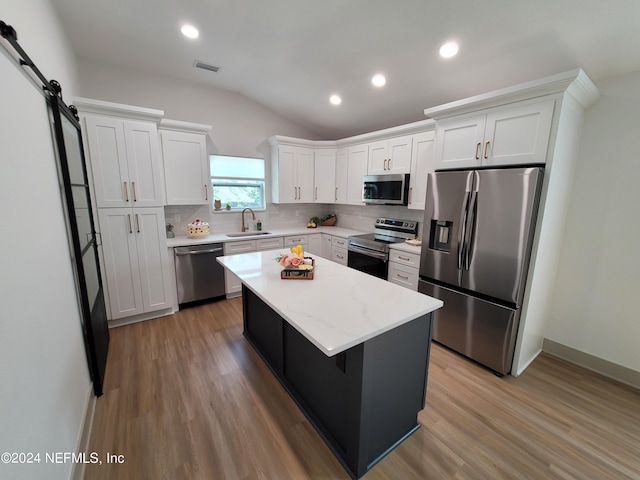 kitchen with light hardwood / wood-style flooring, appliances with stainless steel finishes, a center island, tasteful backsplash, and sink