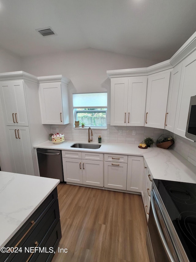 kitchen with lofted ceiling, tasteful backsplash, stainless steel appliances, and light hardwood / wood-style floors