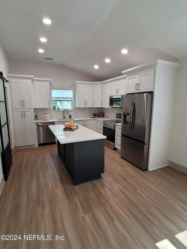 kitchen with sink, stainless steel appliances, a center island, and hardwood / wood-style floors