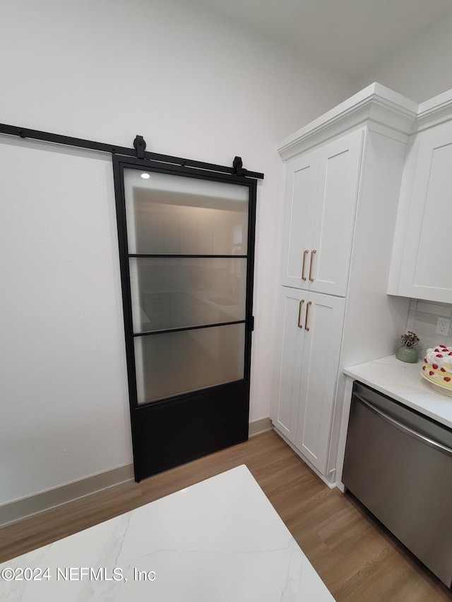 interior space featuring a barn door, hardwood / wood-style flooring, and stainless steel dishwasher