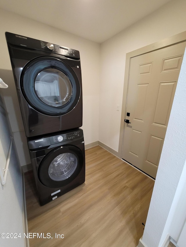 clothes washing area with light wood-type flooring and stacked washer / dryer