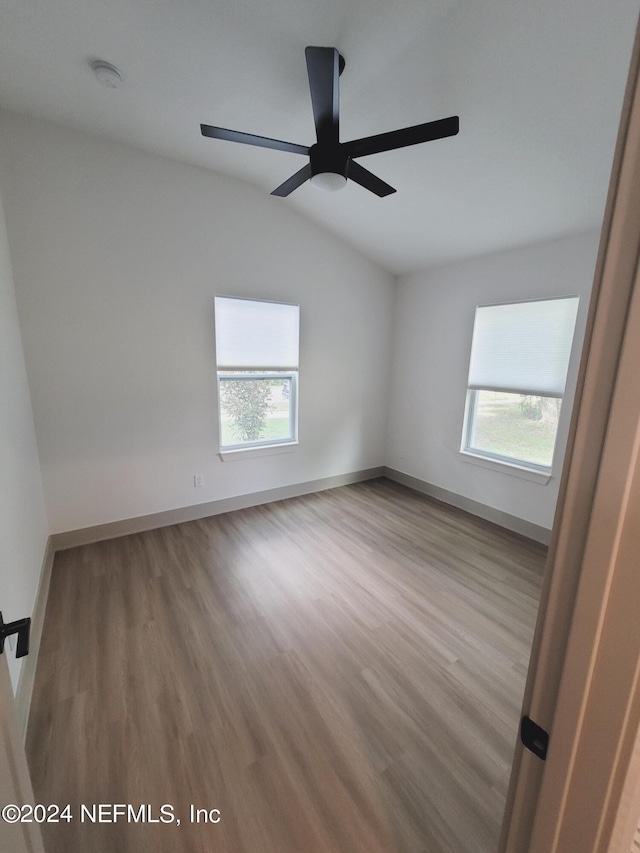 empty room featuring lofted ceiling, light wood-type flooring, and ceiling fan