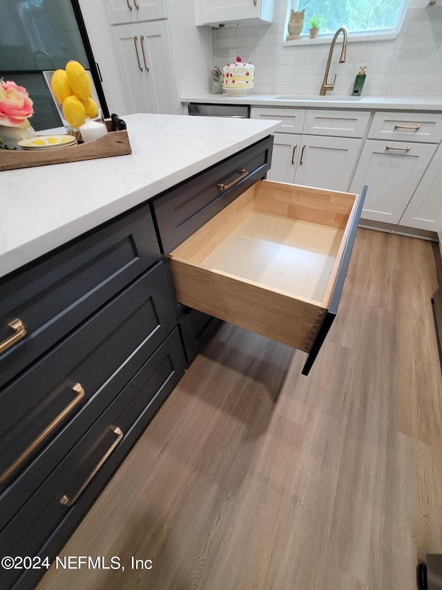 kitchen featuring decorative backsplash, light hardwood / wood-style flooring, sink, and white cabinetry