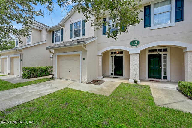 view of property with a garage and a front lawn