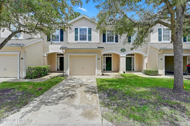 view of property featuring a garage and a front lawn