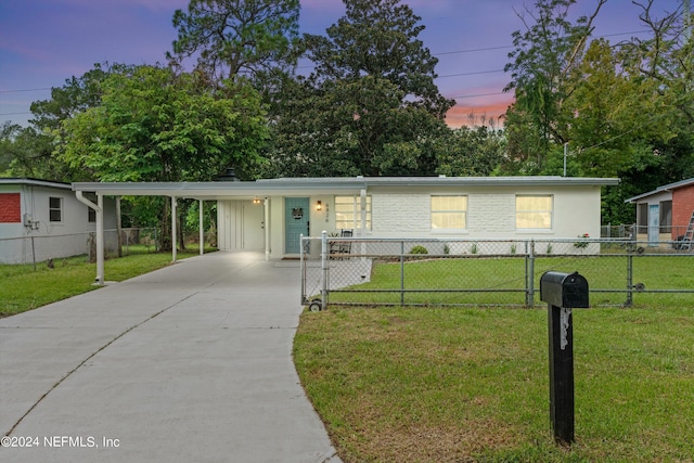 view of front of home with driveway, a carport, fence, and a lawn