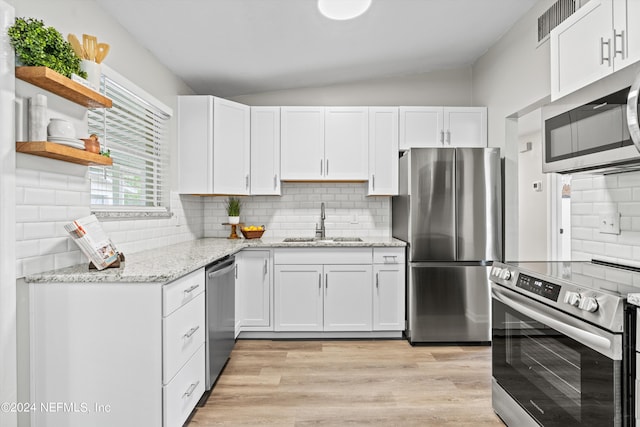 kitchen with a sink, white cabinets, vaulted ceiling, appliances with stainless steel finishes, and open shelves