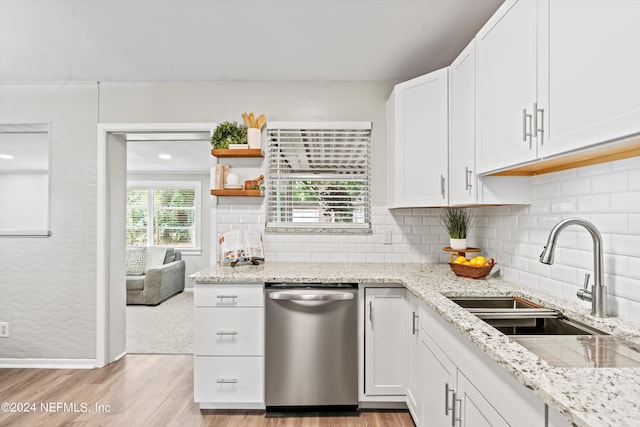 kitchen featuring dishwasher, light stone counters, backsplash, white cabinetry, and a sink