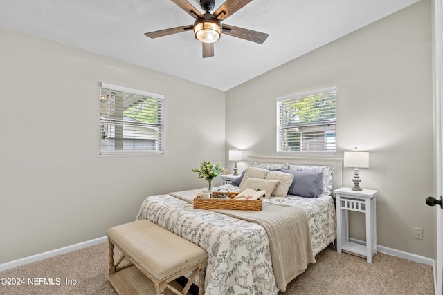 bedroom with lofted ceiling, multiple windows, baseboards, and light colored carpet