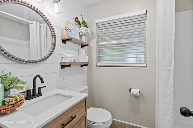 bathroom with toilet, curtained shower, wooden walls, and vanity