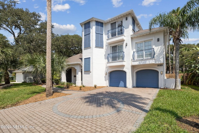 mediterranean / spanish house with a balcony, a garage, and a front yard