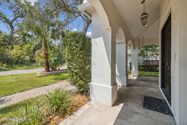 view of exterior entry featuring a yard and a porch