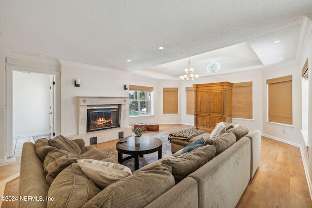 living room with a high end fireplace, ornamental molding, light hardwood / wood-style floors, and a chandelier