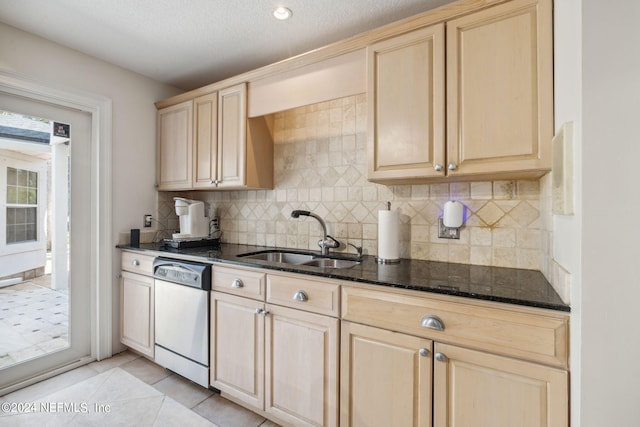 kitchen featuring sink, light tile patterned floors, light brown cabinets, dark stone countertops, and dishwasher