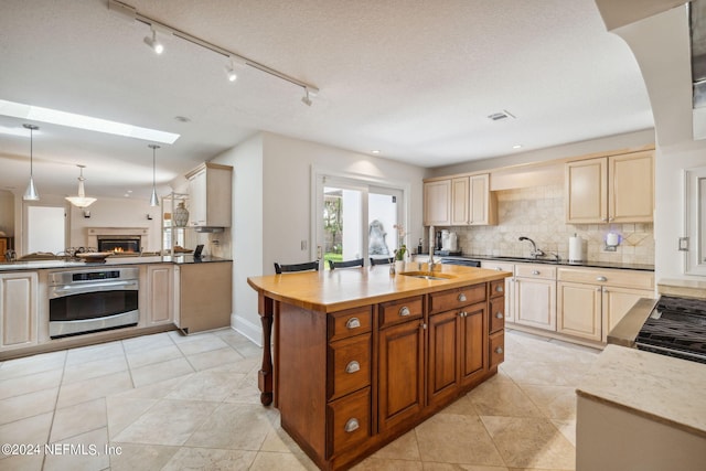 kitchen with pendant lighting, sink, backsplash, a textured ceiling, and oven