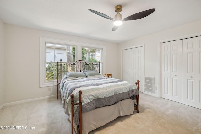 carpeted bedroom with multiple closets and ceiling fan