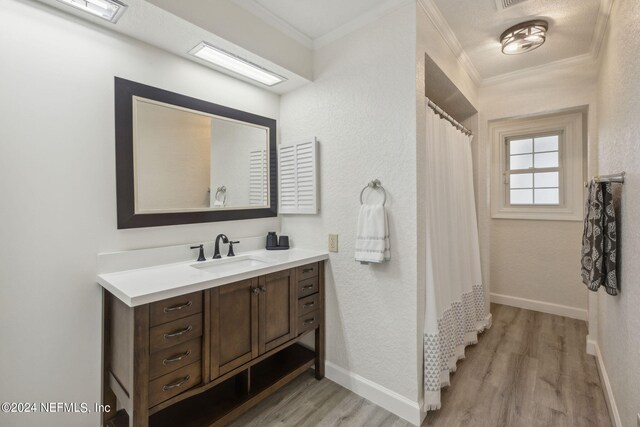 bathroom featuring crown molding, hardwood / wood-style floors, and vanity