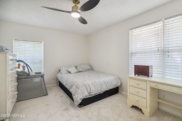 carpeted bedroom with ceiling fan and a textured ceiling