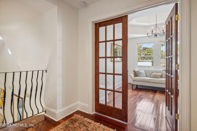 doorway with dark hardwood / wood-style floors and a notable chandelier