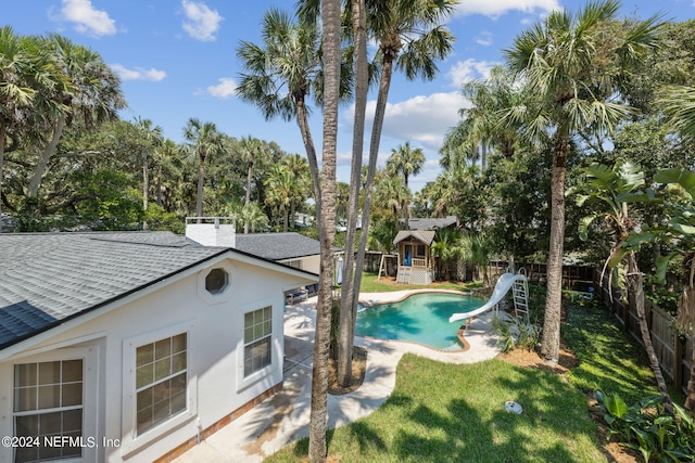 view of pool featuring a yard, a water slide, and a patio area