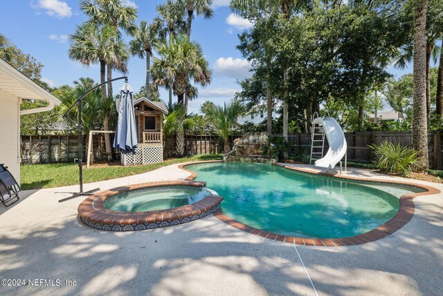 view of pool with an in ground hot tub, a water slide, and a patio area