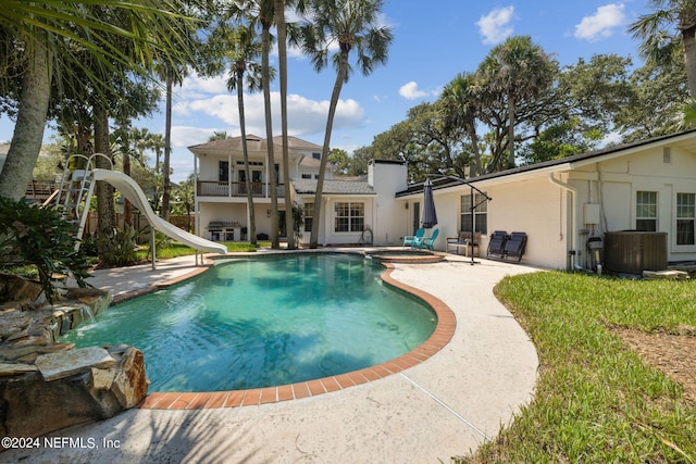 view of swimming pool featuring an in ground hot tub, a water slide, central AC, and a patio area