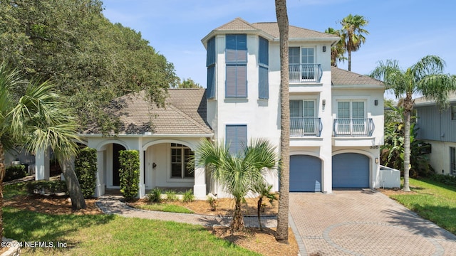 view of front of home with cooling unit, a balcony, a garage, and a front lawn