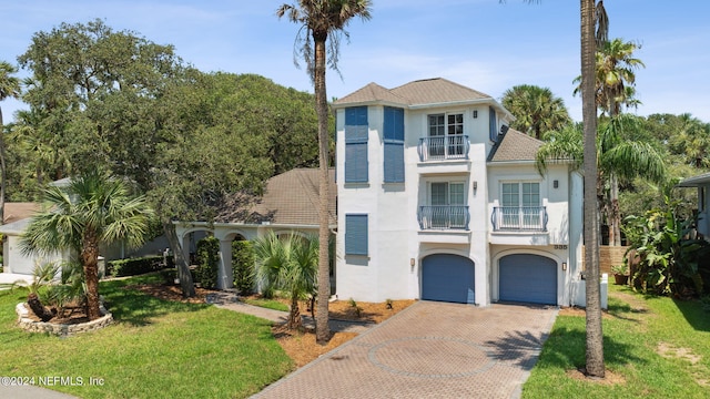 view of front of house featuring a garage, a front lawn, and a balcony