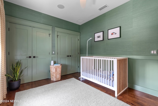 unfurnished bedroom with a closet, ceiling fan, dark hardwood / wood-style floors, and a crib