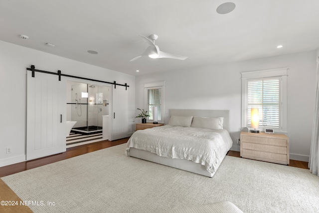 bedroom featuring a barn door, ceiling fan, and dark hardwood / wood-style flooring