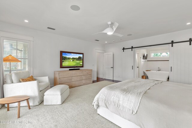 bedroom featuring a barn door, ceiling fan, and hardwood / wood-style flooring