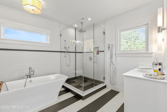 bathroom with vanity, tile walls, tile patterned floors, and shower with separate bathtub