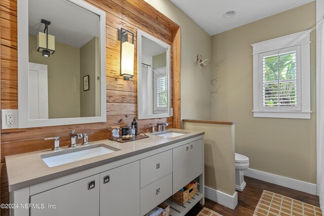 bathroom featuring vanity, toilet, wood walls, and wood-type flooring