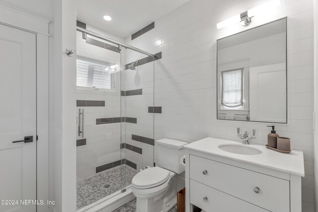 bathroom featuring vanity, walk in shower, tasteful backsplash, tile walls, and toilet