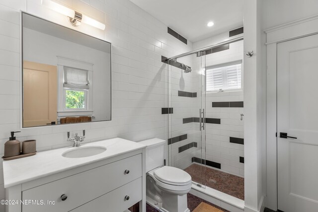 bathroom featuring toilet, walk in shower, vanity, tasteful backsplash, and tile walls