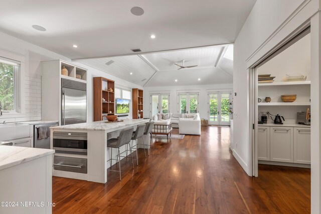 kitchen with lofted ceiling, a healthy amount of sunlight, dark hardwood / wood-style flooring, and white cabinetry