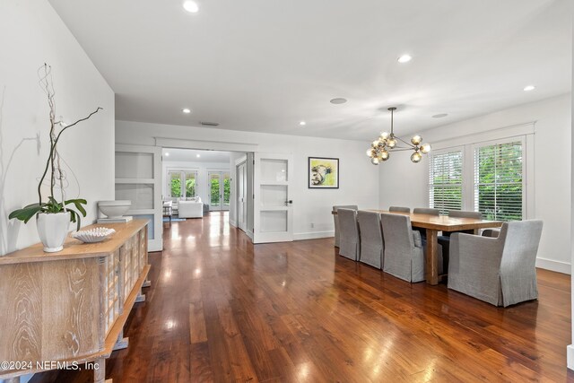 dining area with plenty of natural light, an inviting chandelier, and dark hardwood / wood-style floors