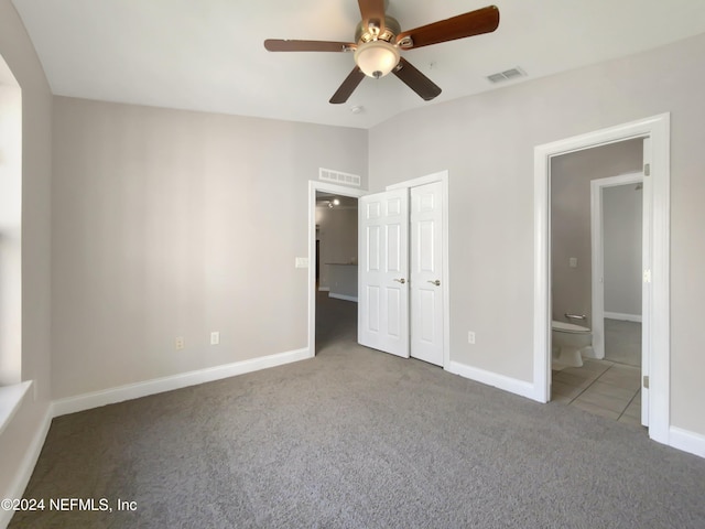 unfurnished bedroom featuring lofted ceiling, ensuite bath, ceiling fan, carpet flooring, and a closet