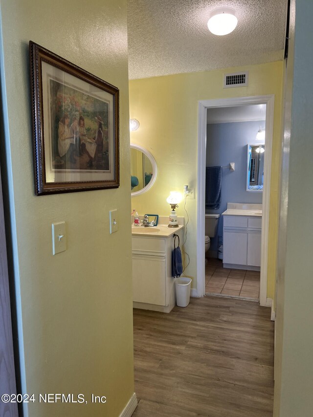 hall featuring a textured ceiling and hardwood / wood-style flooring