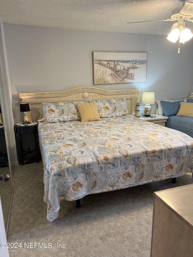 carpeted bedroom featuring ceiling fan and a textured ceiling