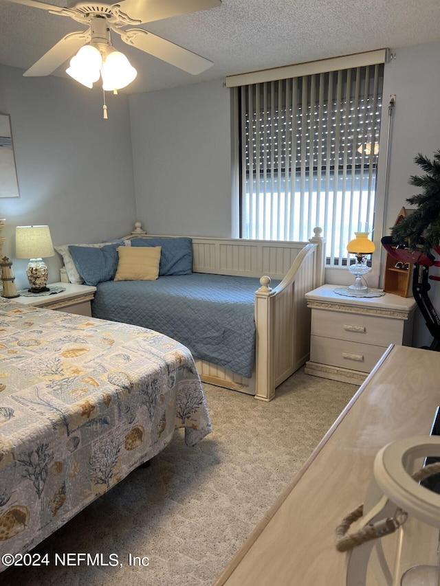 bedroom with ceiling fan, a textured ceiling, and light colored carpet