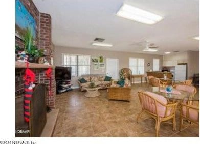 tiled living room featuring ceiling fan and brick wall