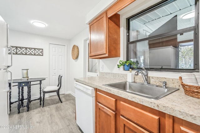 kitchen with light wood-type flooring, white appliances, and sink