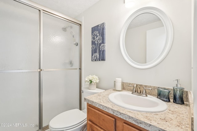 bathroom featuring an enclosed shower, vanity, a textured ceiling, and toilet