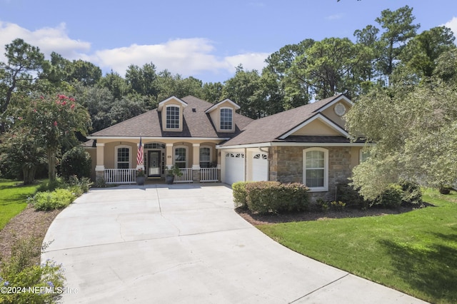 view of front facade featuring a garage, concrete driveway, stone siding, covered porch, and a front lawn