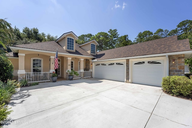 view of front of house featuring a porch, concrete driveway, stone siding, and a garage