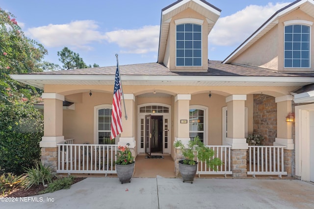 exterior space featuring stone siding, covered porch, roof with shingles, and stucco siding