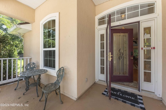 doorway to property with covered porch and stucco siding