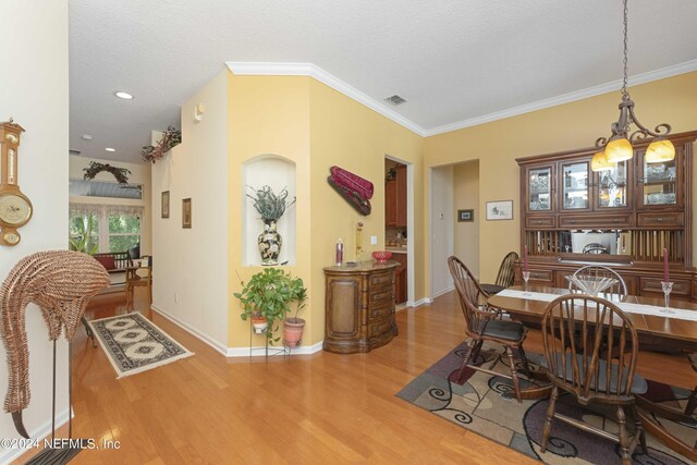 dining room featuring a textured ceiling, crown molding, a chandelier, and hardwood / wood-style flooring